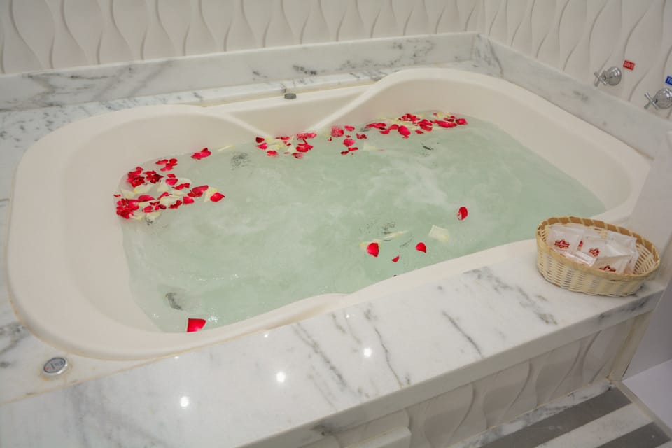 Banheira de hidromassagem com pétalas de rosa na suíte do Hotel Rouxinol